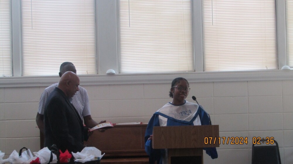 A couple people standing next to a graduate behind a podium.