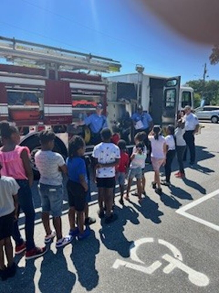 A line of kids in front of a fire truck.