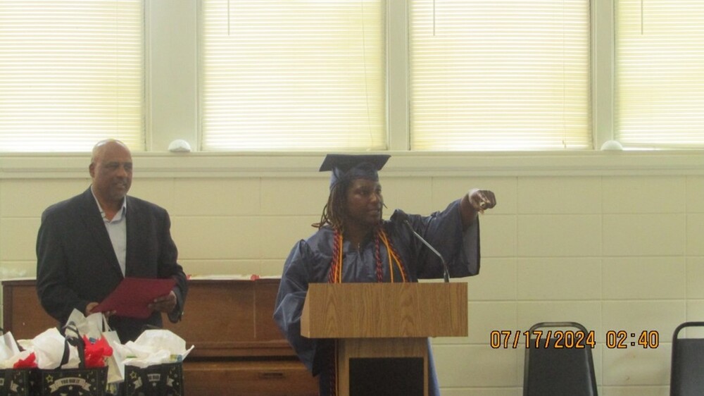 A man standing next to one of the 2024 graduates.