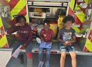 Some kids sitting on the back of a fire truck.